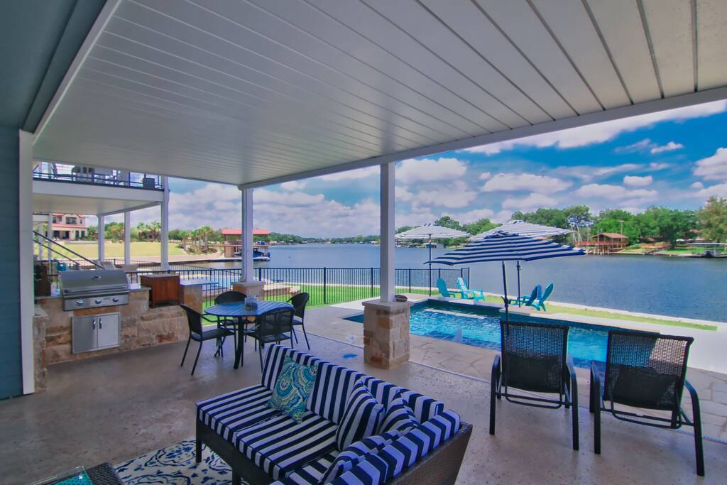 Covered patio with outdoor gas grill, sofas, chaise lounges, table with seating for 4, bar cart, child sized table and chairs