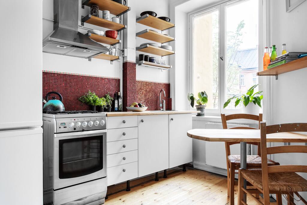 Kitchen with table and four chairs, gas stove, electric oven, fridge and freezer, cold storage for more food.
