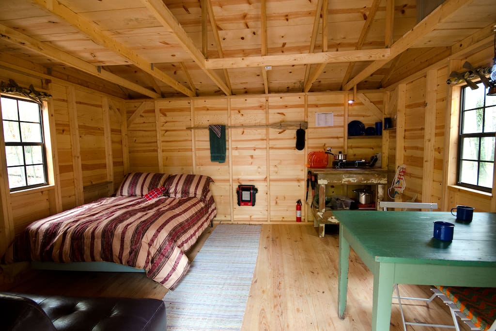 Hut interior. Double bed, dining table, kitchen area. Also a couch that folds to another double bed.