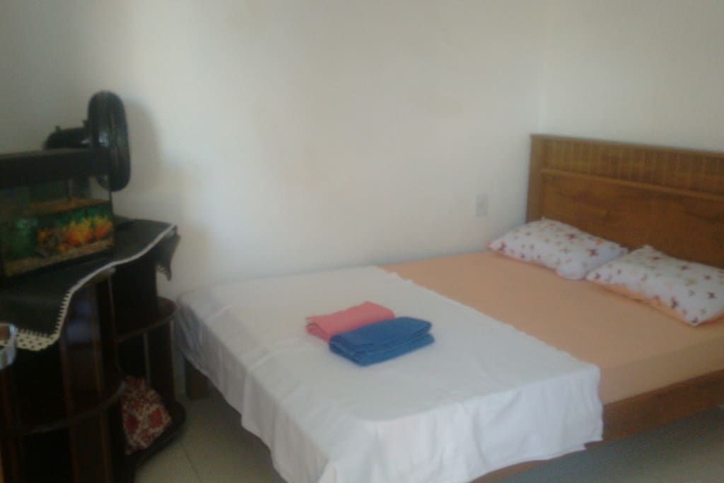 Uma quarto com cama de casal .cortinas..e ventilador..