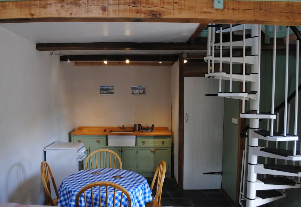 hand made free standing kitchen and dining area with shower room and spiral stairs on the right.