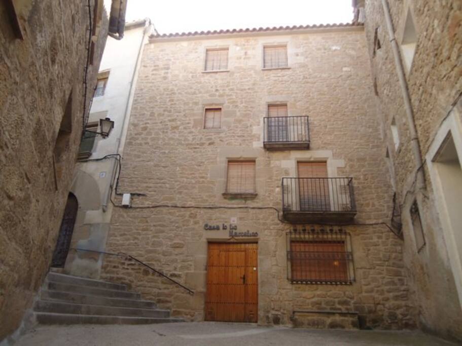 Entrada con plazoleta y banco de piedra.