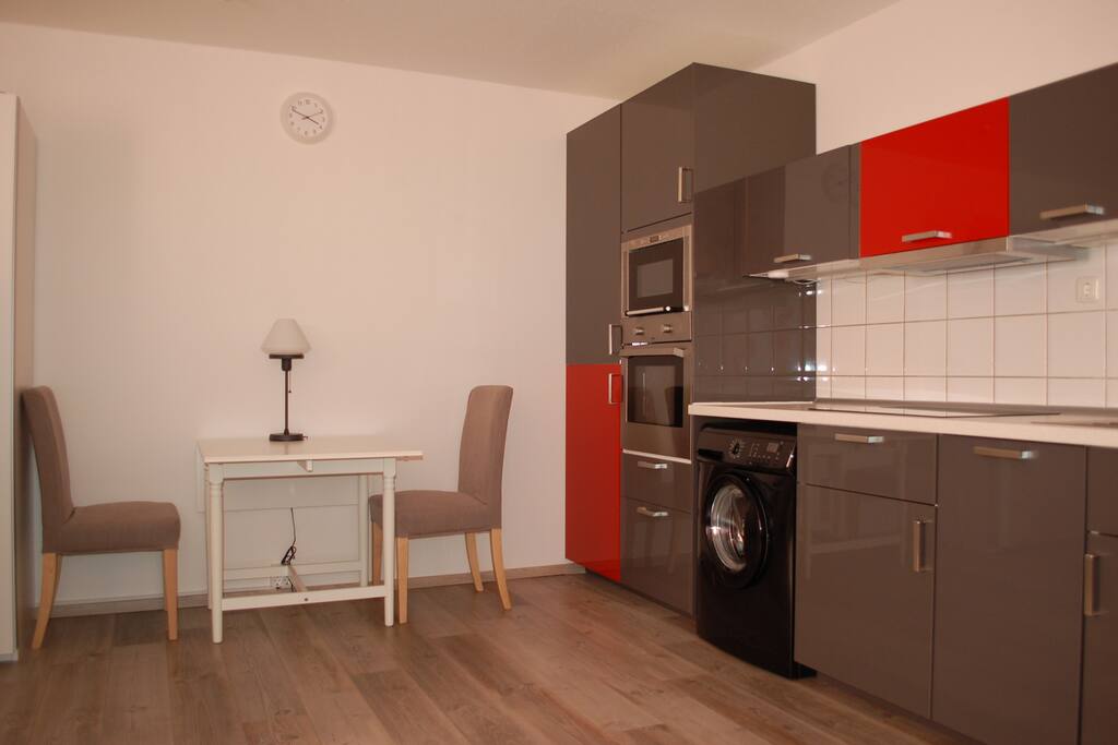 Moderne Küchenzeile mit Mikrowelle, Kühlschrank, Backofen und Waschmaschine