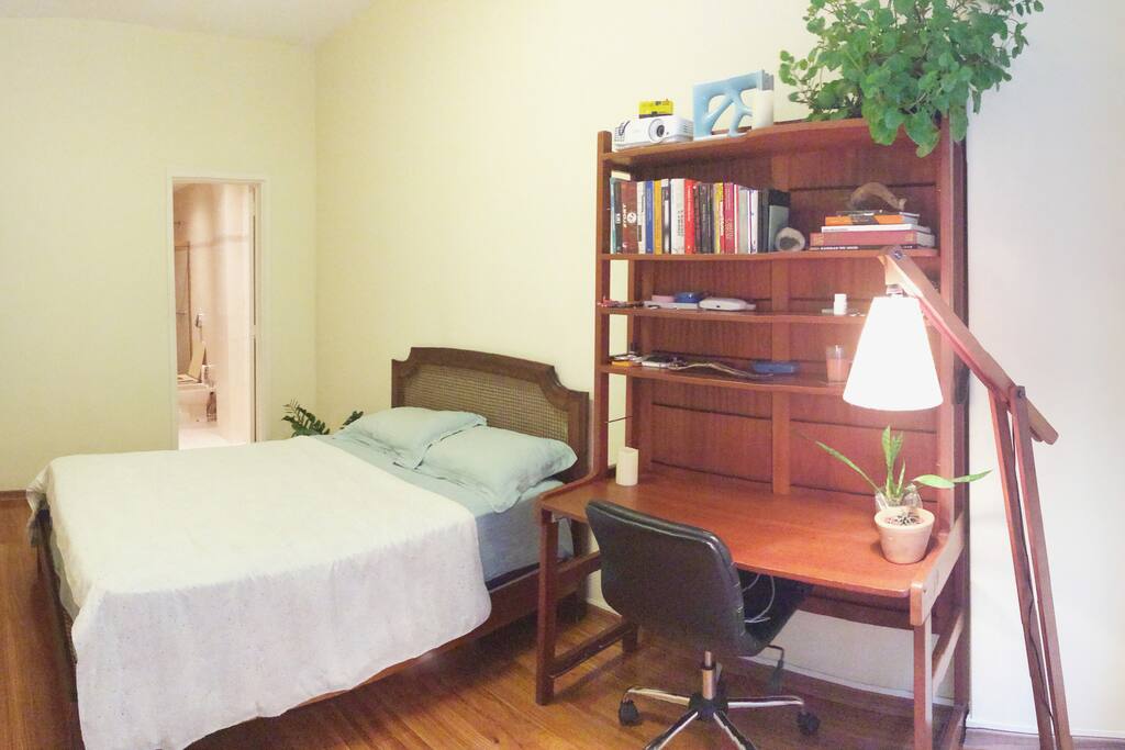 Quarto com mesa de trabalho e banheiro privativo