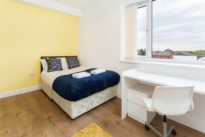 Discover comfort in our corner bedroom, where you'll find a plush bed, crisp linens, and a convenient desk for your work or study needs. The large window floods the room with natural light.