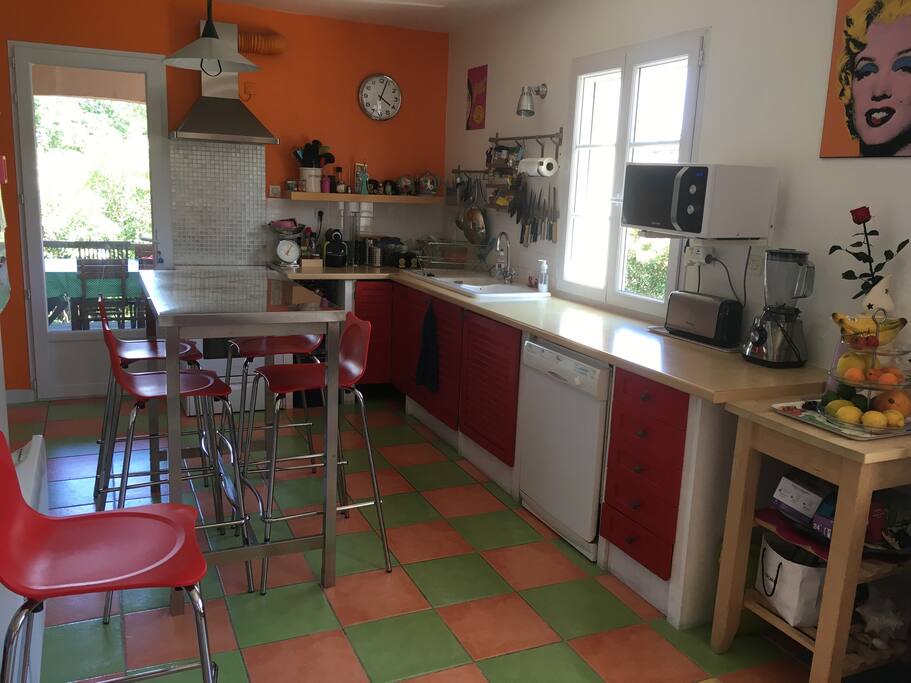 Cuisine équipée donnant sur terrasse couverte pour petit déjeuner, déjeuner et dîner dehors avec salon de jardin, plancha, baby-foot et table de ping-pong.