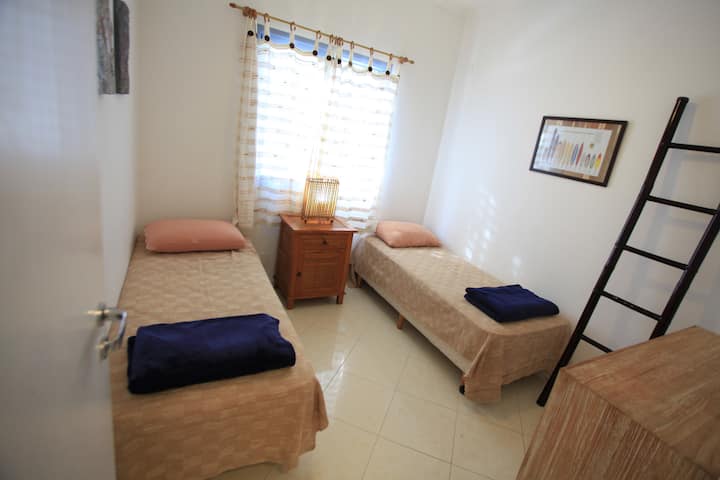 一楼舒适的房间，无需使用楼梯，配有空调和无电视吊扇。 床可以合并，适合1对情侣。 窗户可看到房子前面的景观。 房间紧邻卫生间和走廊的洗衣房。