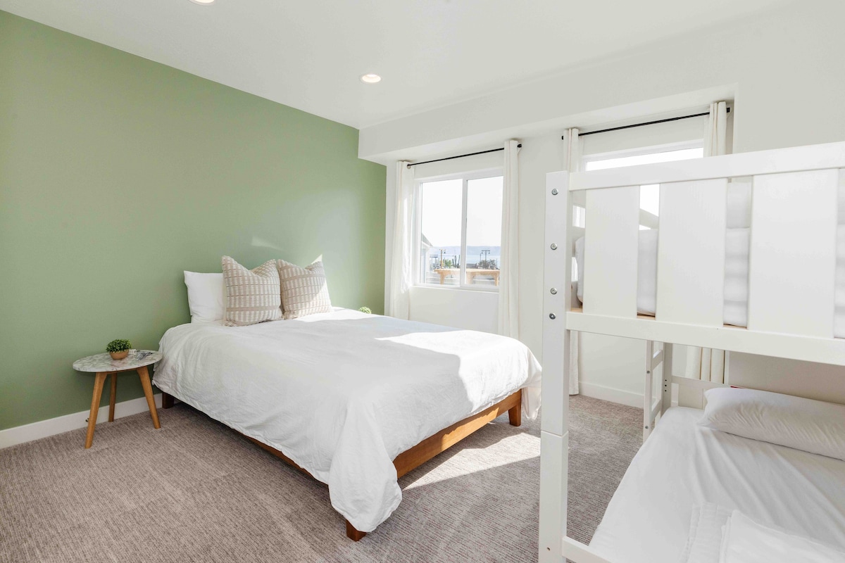 Spálňa č.2 zahŕňa hybridný matrac Queen, bambusovú posteľnú bielizeň, dvojité poschodové postele, zrkadlo po celej dĺžke a pracovnú stanicu na stole.