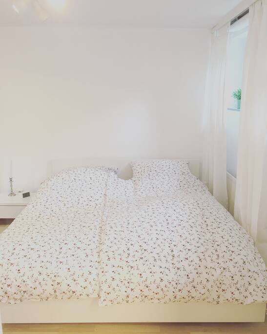 Das Schlafzimmer - Doppelbett im hellen Raum und ein sehr großer Spiegel ist auf der linken Seite (direkt an einem Kleiderschrank)