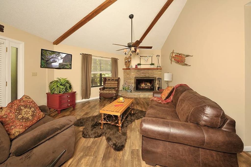 A open living room with a fold out sofa and a wood burning fireplace.