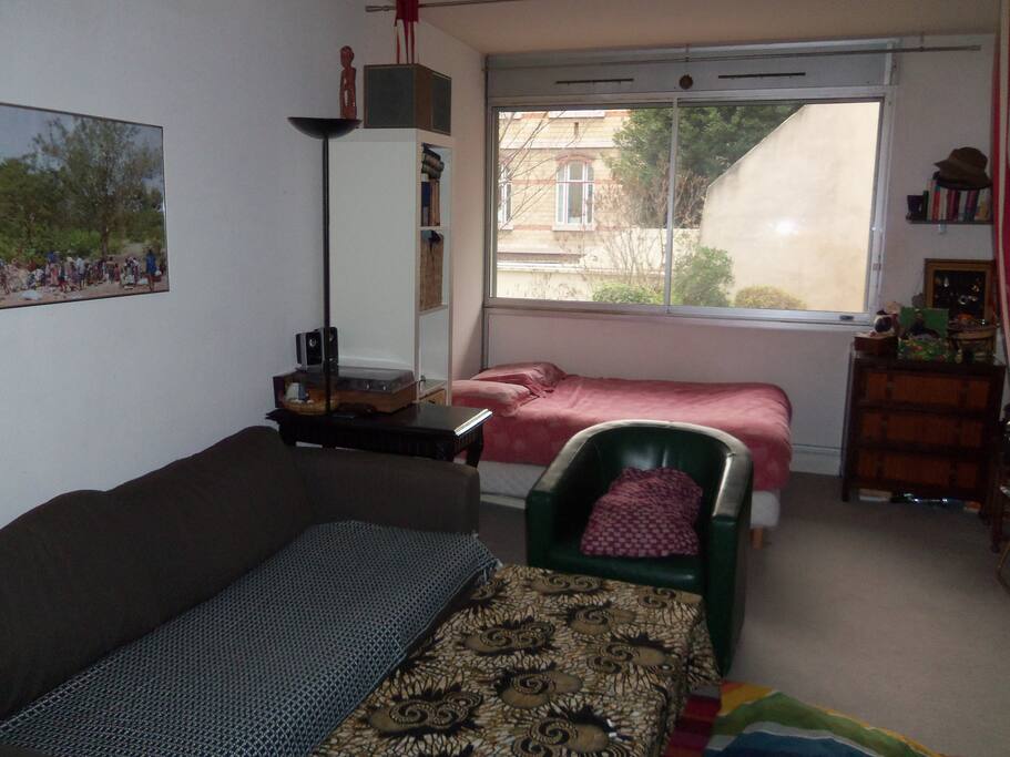 Espace salon et chambre qui se separent par des rideaux