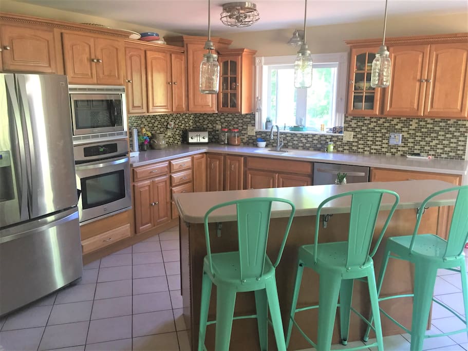 Big, open kitchen, double sink, high counter, three stools.