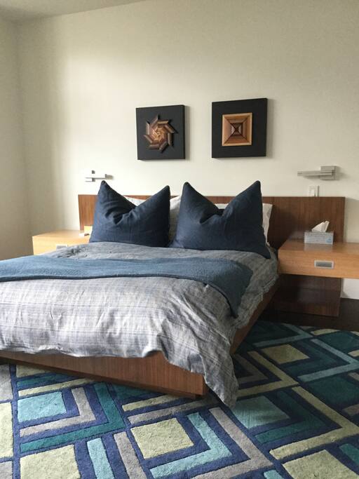Queen bed with organic mattress, luxury Sferra bedding, attached nightstands and wall mounted adjustable reading lights