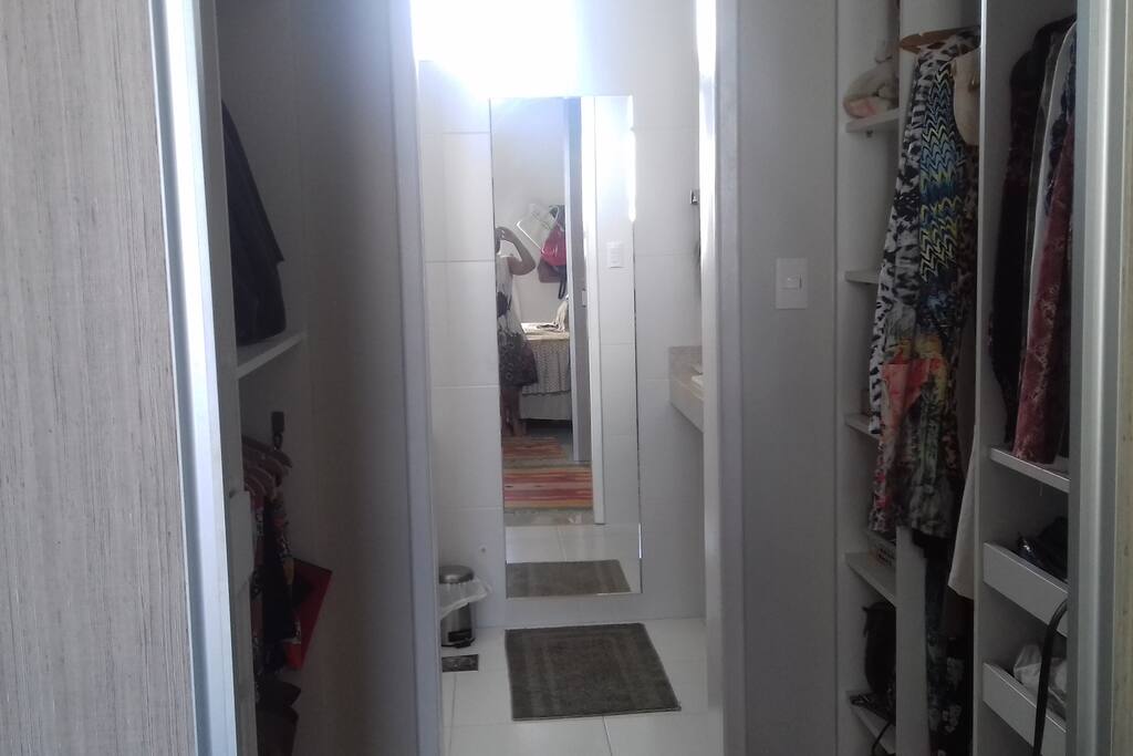 Um closet e no interior um.banheiro muito amplo com espelho