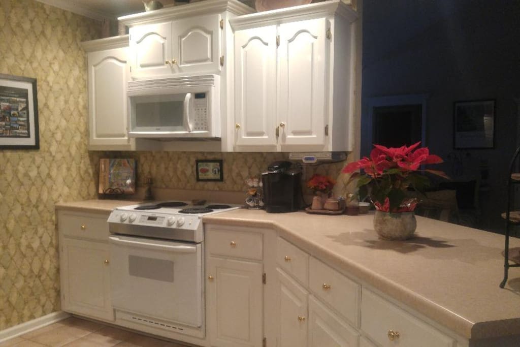Microwave above electric stove counter with 2 bar stools on opposite side