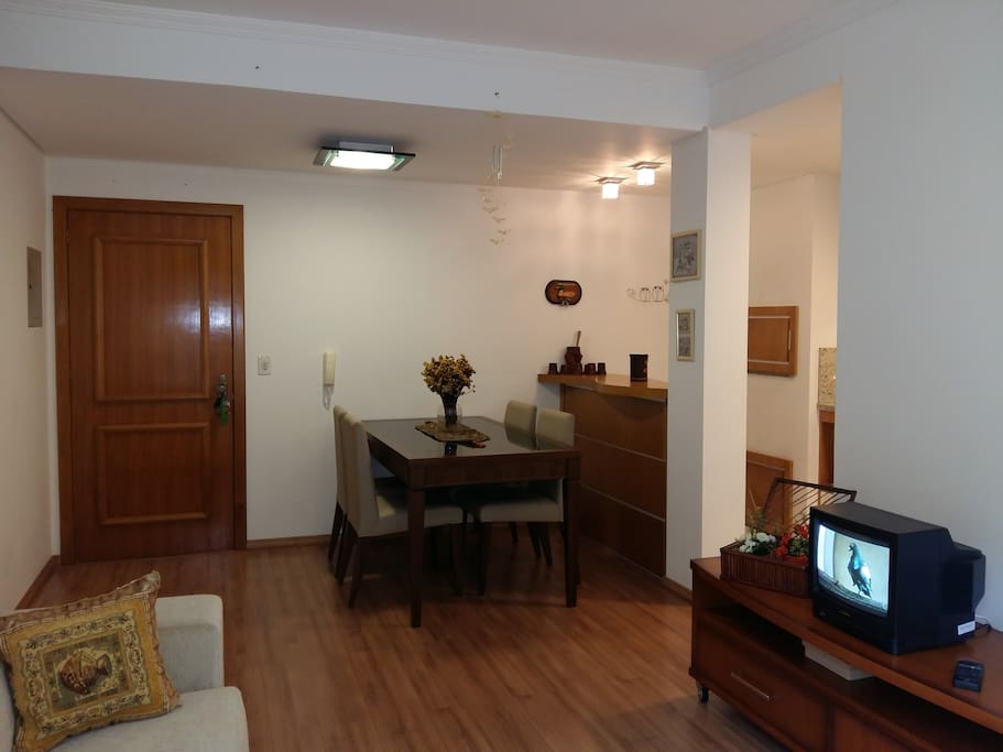 Sala de estar com televisão e sala de jantar para 04 pessoas.