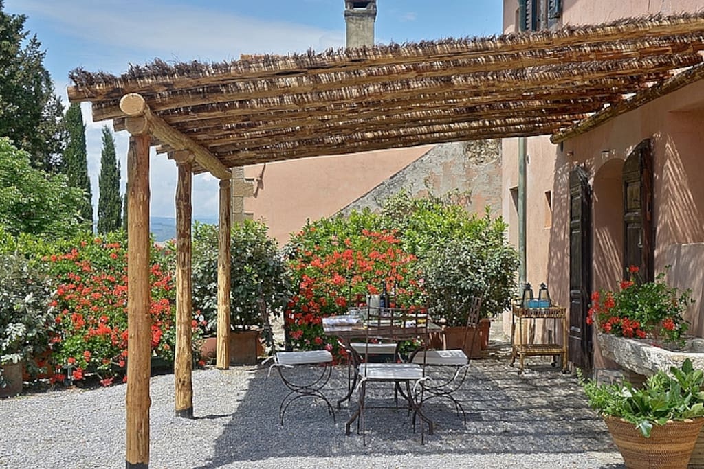 Outdoor dining area under pergola surrounded by lovely garden