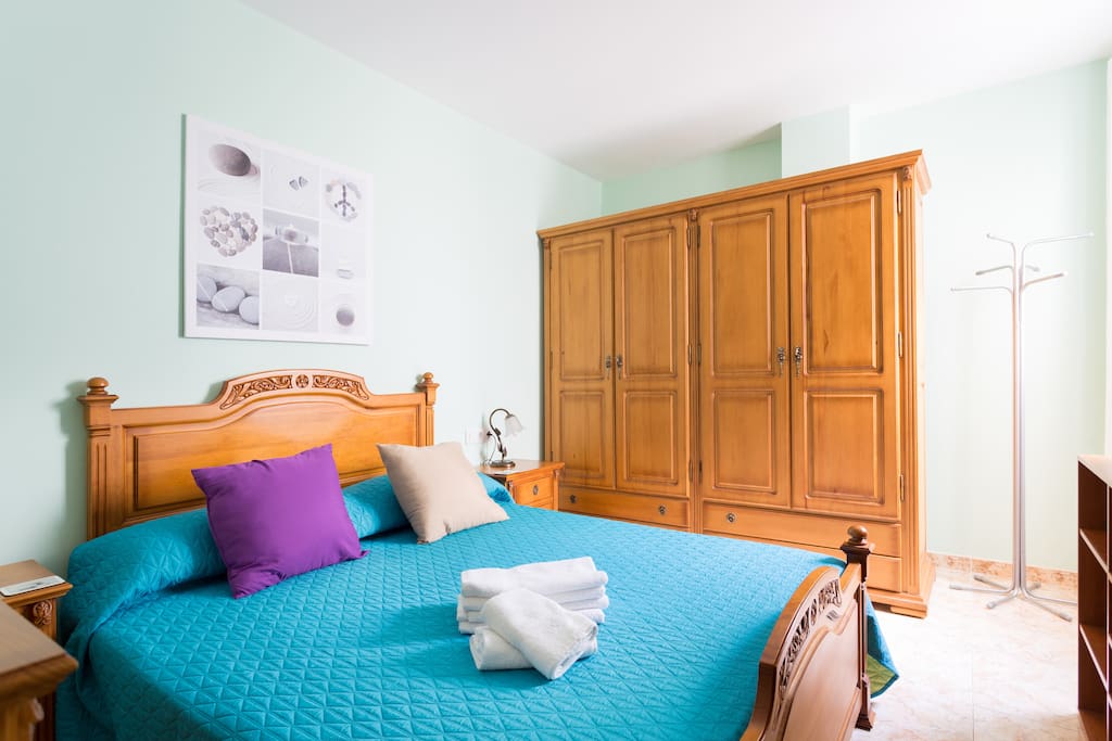 Habitación principal iluminada con cama matrimonial más armario.