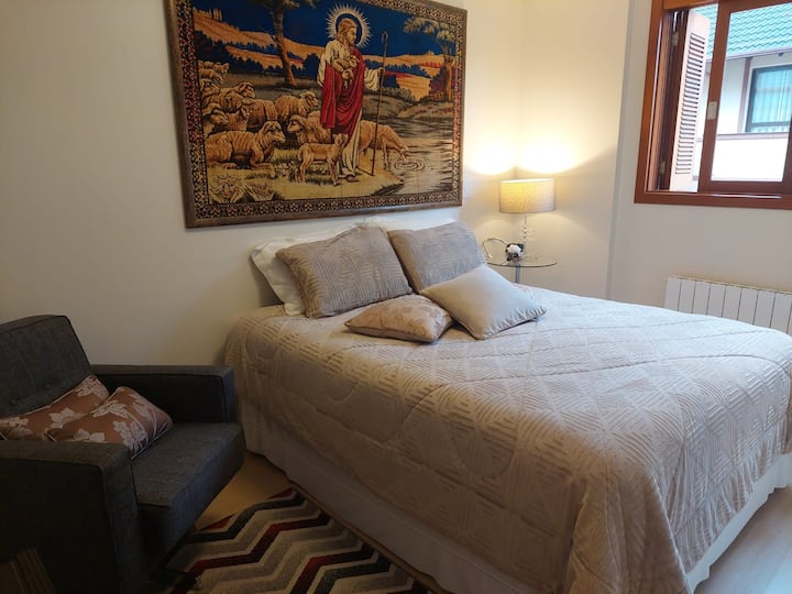 Quarto suite aconchegante com cama queen, ar-condicionado, roupas de cama de qualidade, blackout e espaço para guardar suas malas.