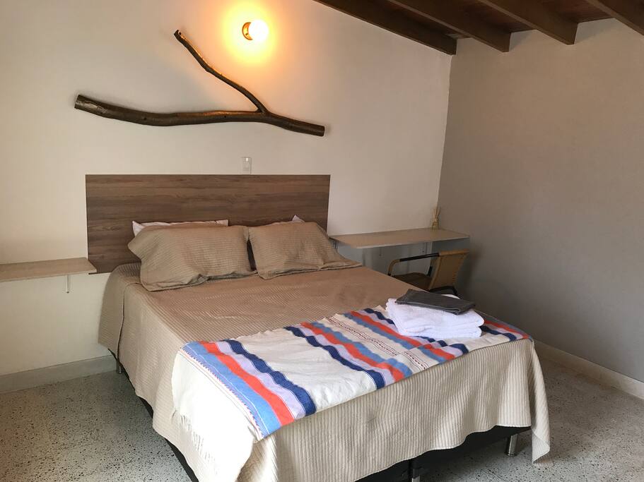 The room features a queen pillow top bed and a desk.