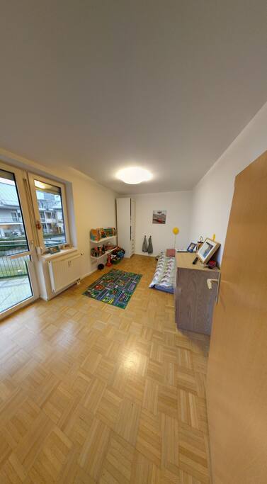 our son's room with a low single bed and an entrance to the smaller balcony