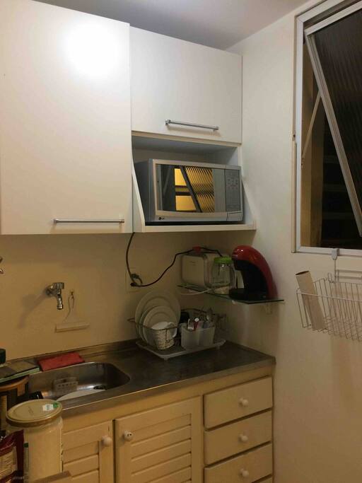 Porta a primeira esquerda do corredor: COZINHA equipada com microondas, cafeteira, fogão, máquina de lavar, tanque e geladeira.