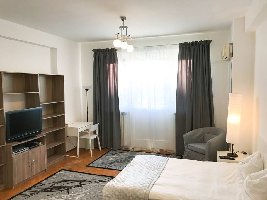LCD TV, desk space in the left corner of the room and behind the curtains is the access door to the balcony.