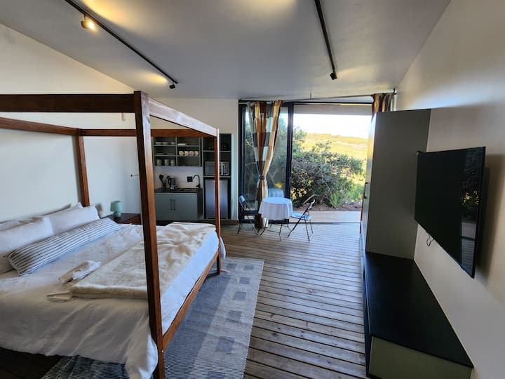 Villa en la planta baja a través de entrada independiente. Equipado con una cama tamaño queen de cuatro postes, cocina pequeña, baño abierto y TV inteligente.  La mejor experiencia interior/exterior con suelo de madera y vistas a la naturaleza y al mar.