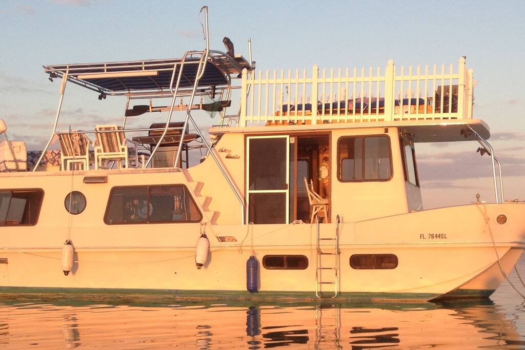 Houseboat has white picket fence on upper roof and custom tee top