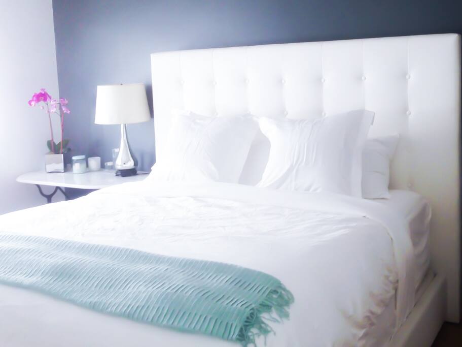 Bedroom with Four Seasons Hotel King sized bed, feather and down duvet and pillows and 47" Samsung flatscreen smart TV.