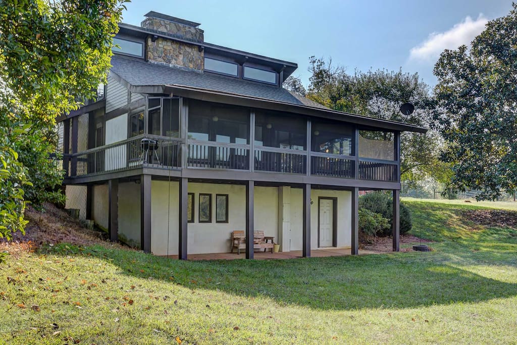 Backside of house with screened-in porch and walk-out basement with covered patio.