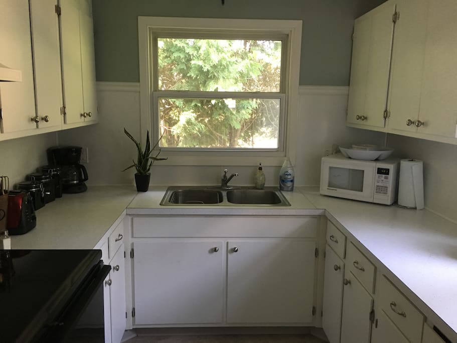Full kitchen with electric range. Dishes and glassware