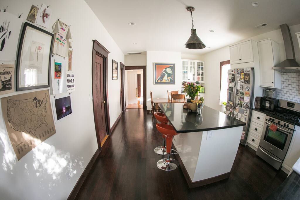 Kitchen filled with natural light, marble countertops, hardwood floors, new appliances, and a view of the trees in the backyard.