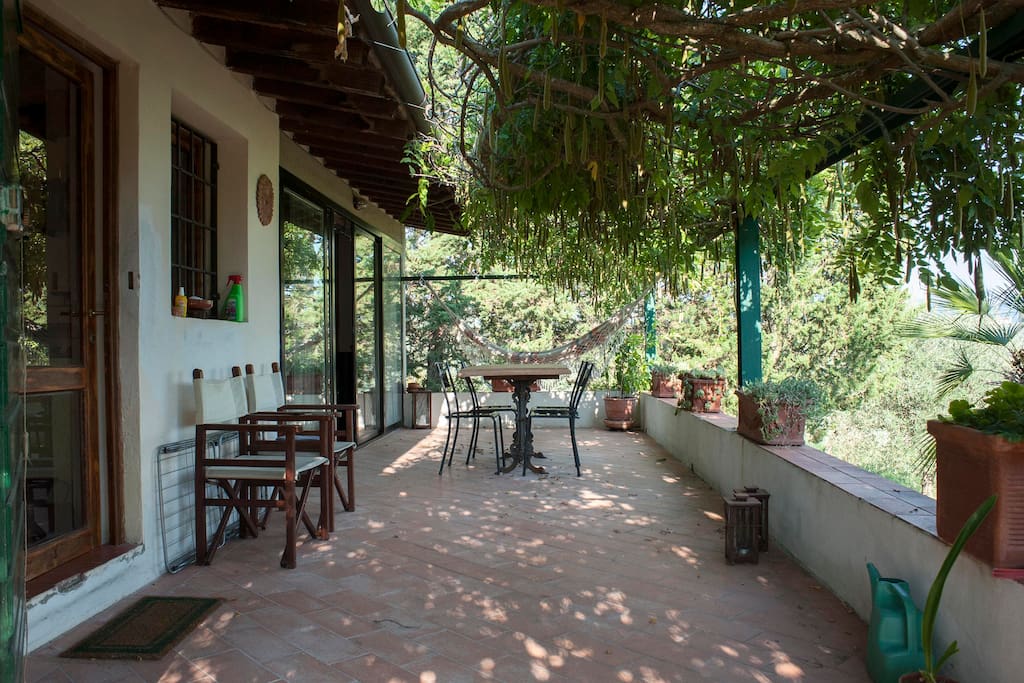 Terrazza in cotto con sediie e tavolo in marmo da esterni. Pergola in glicine