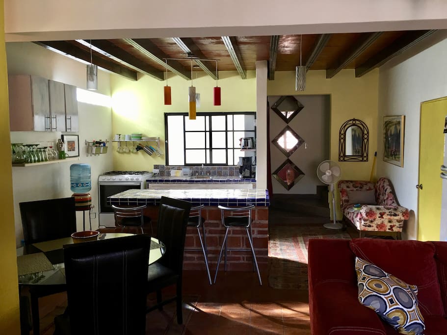 View from the living room into the kitchen/dining area, with nice round glass table with 4 chairs as well as bar stools for the counter.