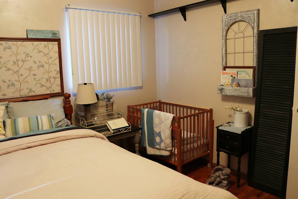 Guest bedroom with small crib. There is also a small chair and a closet.