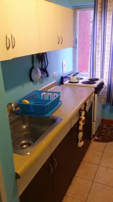 Partial kitchen view with cabinet space, utensils and 4 burner stove