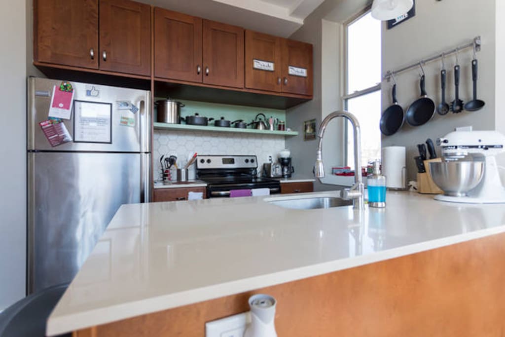 Kitchen has microwave, refrigerator, coffeemaker, tea kettle, and pots and pans