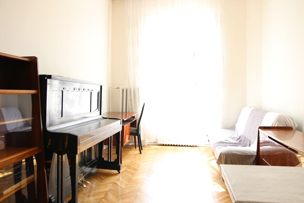Living room - with piano, working desk, dining table and a sofa which can sleep two adults or children.