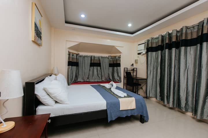 The master bedroom features a queen-sized bed, smart TV, and working table. It has its own bathroom.