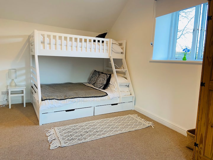 Este espacioso dormitorio tiene una cama doble y una cama individual y también hay espacio para una cuna de viaje aquí. Esta habitación también tiene fantásticas vistas al campo.  También hay un escritorio y una silla en esta habitación.