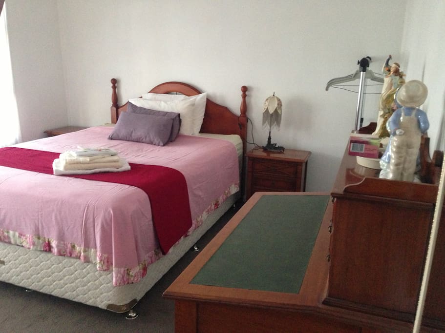 Queen sized sunny bedroom with vintage furniture.