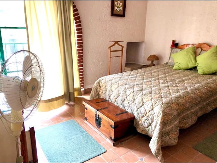 Spálňa so sieťou proti komárom, prenosným ventilátorom a kúpeľňou s toaletou.