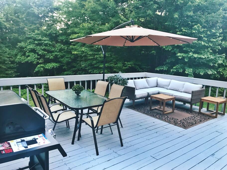 Large deck with 4-burger gas grill, two dining sets, sectional and offset umbrella with LED lights.