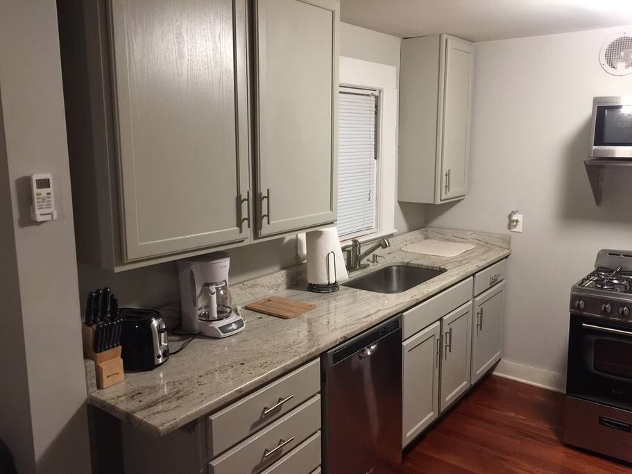 Kitchen with custom cabinets, granite countertops, small gas stove/oven, stainless dishwasher and microwave.