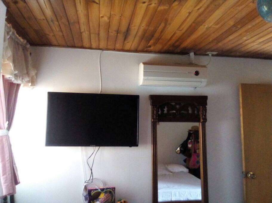 Habitación principal con cama matrimonial tv y aire acondicionado.