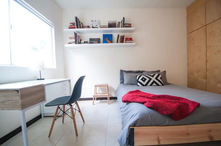 Recamara con cama matrimonial, televisión, escritorio. 