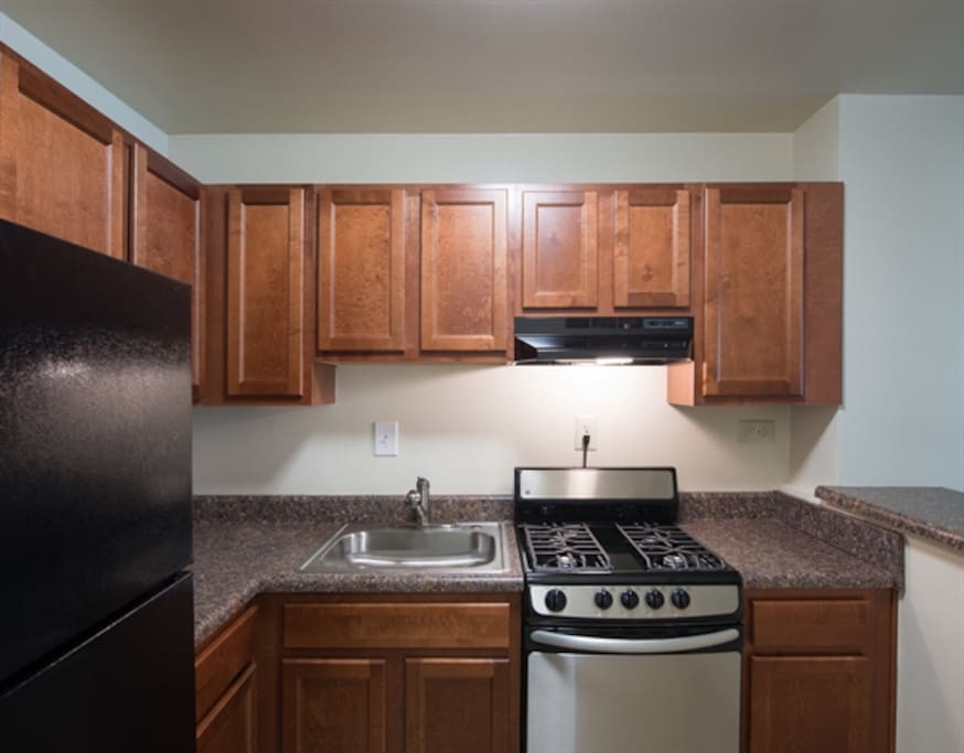 View from the entrance to a spacious full kitchen. The appliances have recently been renovated and will be cleaned and sanitized prior to guest arrival. Kitchenware provided. Included: Full refrigerator with freezer, gas stove and oven and bar with stools. (Updated pictures will be uploaded momentarily).