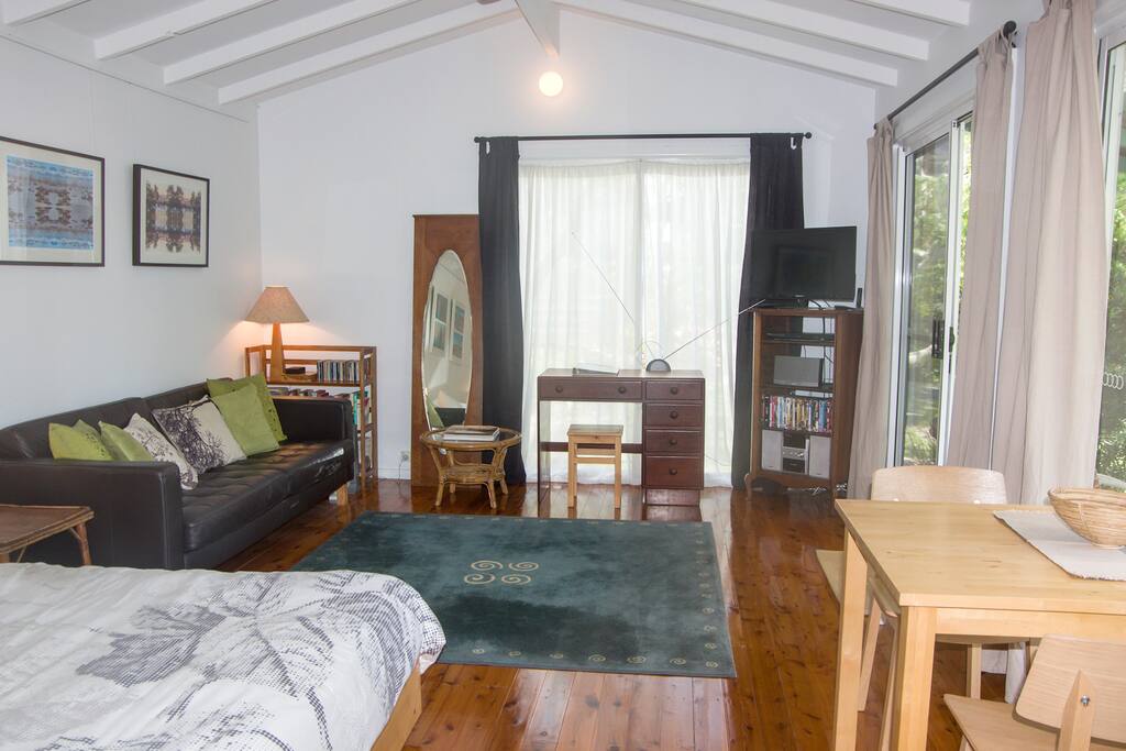Bed-living space with polished floors, raked ceilings and ceiling fan