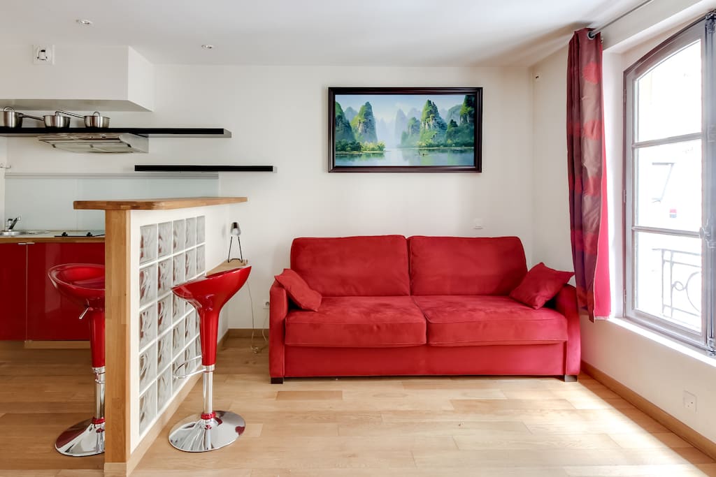 Salon avec canapé, petit bureau et cuisine américaine